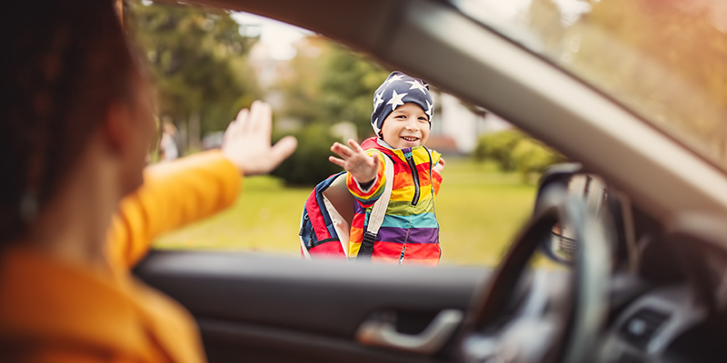 child being dropped off waving at parent in car
